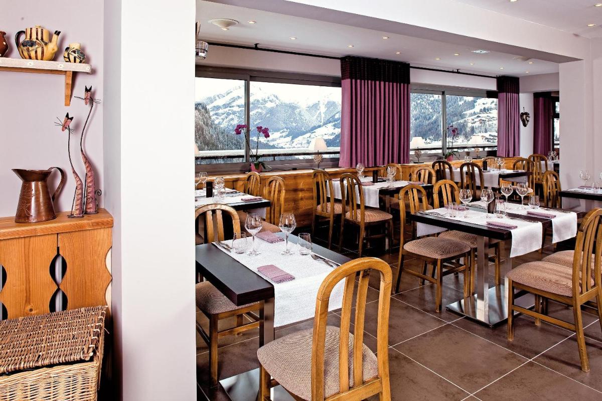 un restaurant avec des tables et des chaises et des montagnes en arrière-plan dans l'établissement Hôtel Belalp, à Châtel