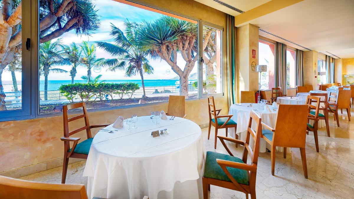 Un restaurante con mesas y sillas y vista al mar. en Bull Reina Isabel & SPA, en Las Palmas de Gran Canaria
