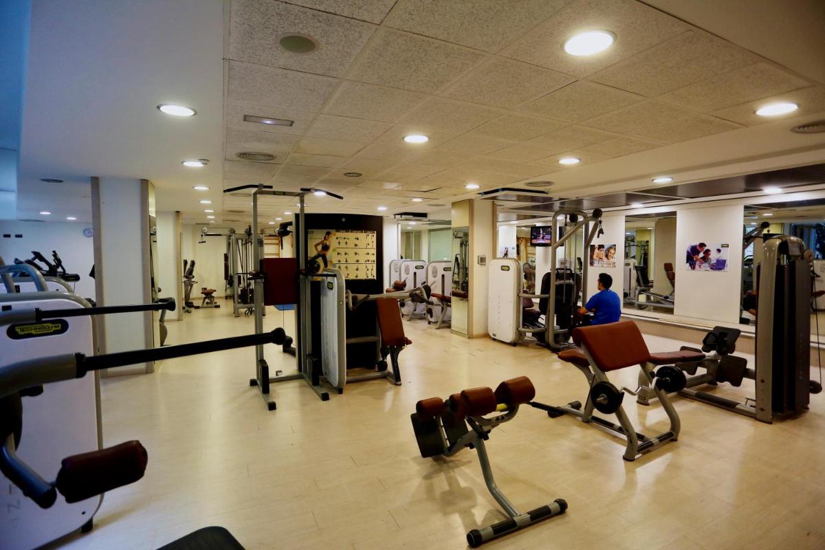 un gimnasio con equipo cardiovascular y un hombre de fondo en Gran Palas Hotel - Spa incluido, en La Pineda
