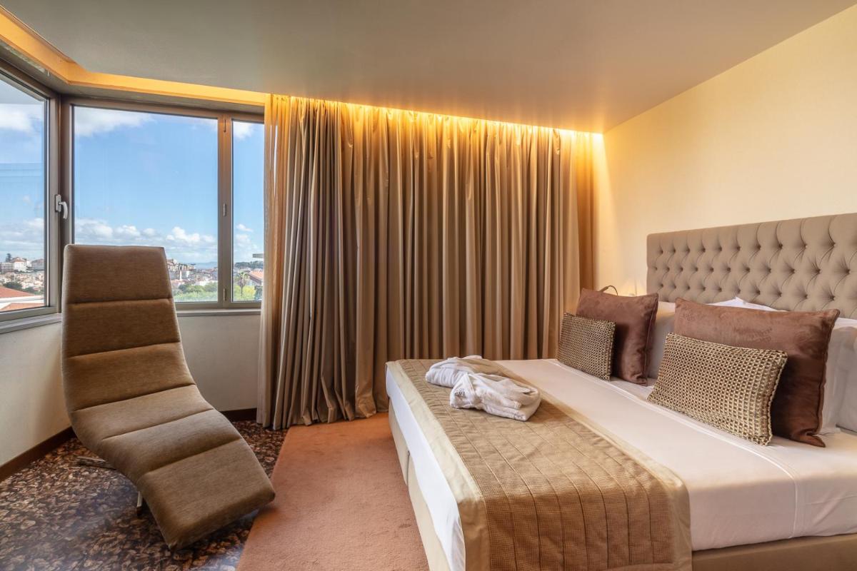 um quarto com uma cama, uma cadeira e janelas em NEYA Lisboa Hotel em Lisboa