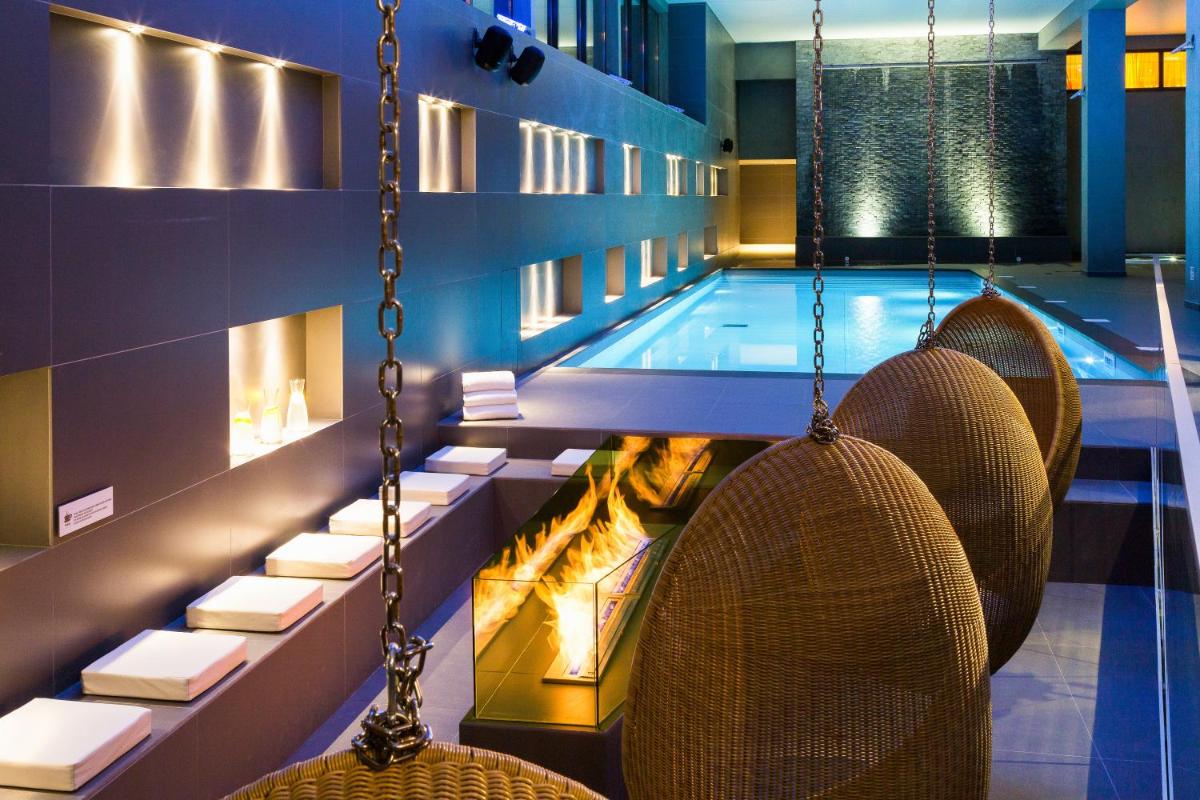 - une piscine avec des chaises et une balançoire dans l'établissement Heliopic Hotel & Spa, à Chamonix-Mont-Blanc