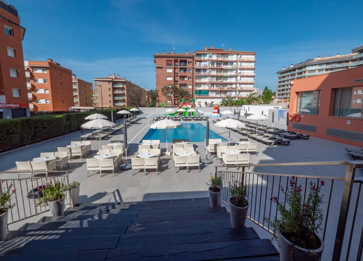 una piscina con sillas y sombrillas en un patio en Fenals Garden, en Lloret de Mar
