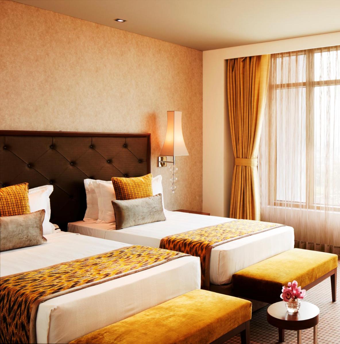 a hotel room with two beds and a window at Taj Swarna, Amritsar in Amritsar