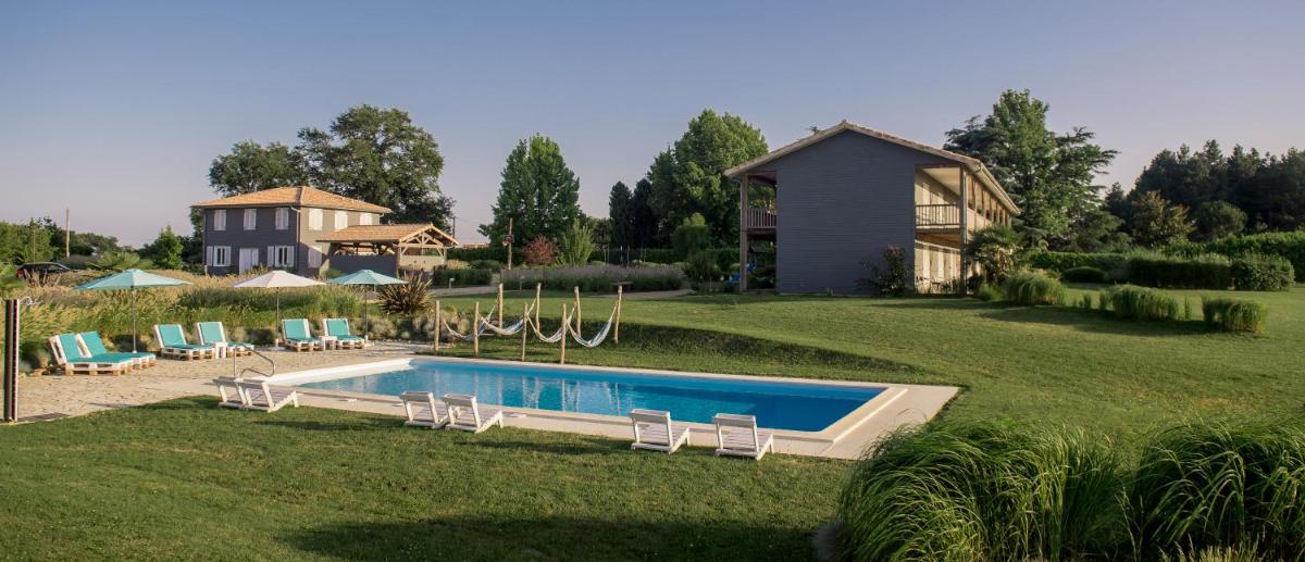 une cour arrière avec une piscine et une maison dans l'établissement La Petite Couronne, Ecolodge & Lofts, à Saint-Cricq-Chalosse