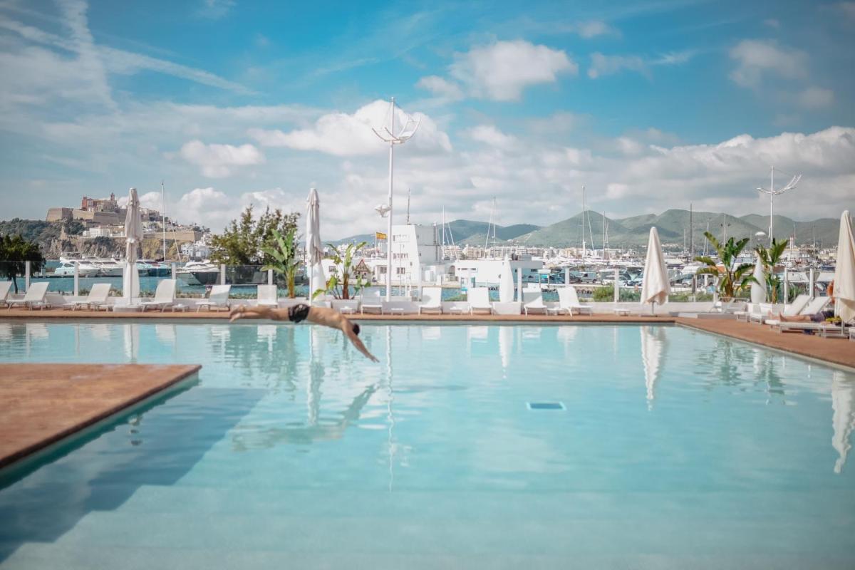 una persona nadando en una piscina con una ciudad al fondo en Ibiza Corso Hotel & Spa, en Ibiza