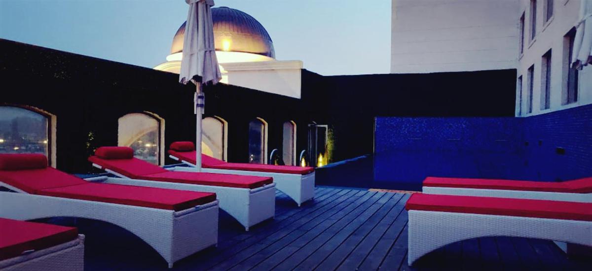 a deck with red and white chairs on a building at Ramada by Wyndham Lucknow Hotel and Convention Center in Lucknow