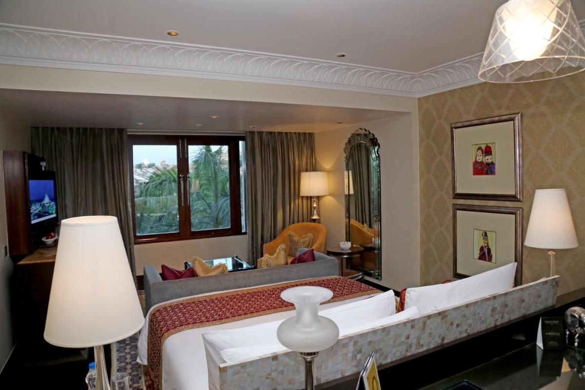 a bedroom with a large bed and a large mirror at The Leela Palace Udaipur in Udaipur
