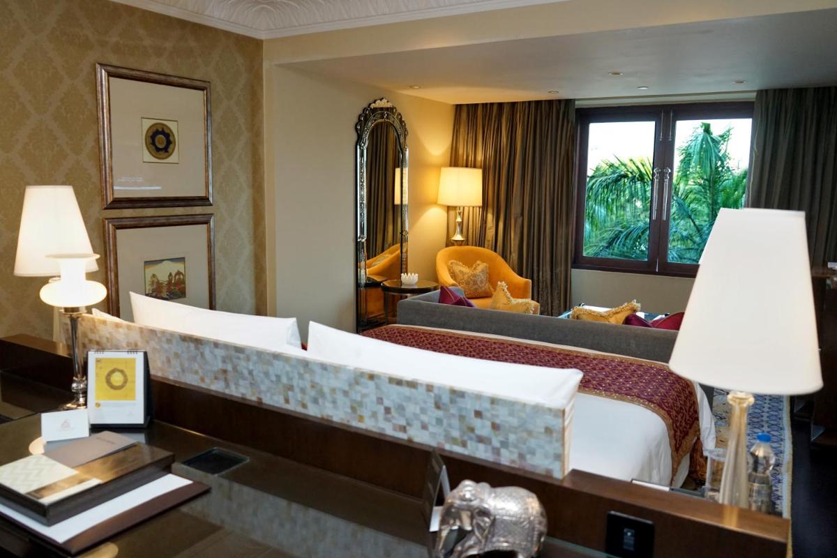 a hotel room with a bed and a desk with a lamp at The Leela Palace Udaipur in Udaipur