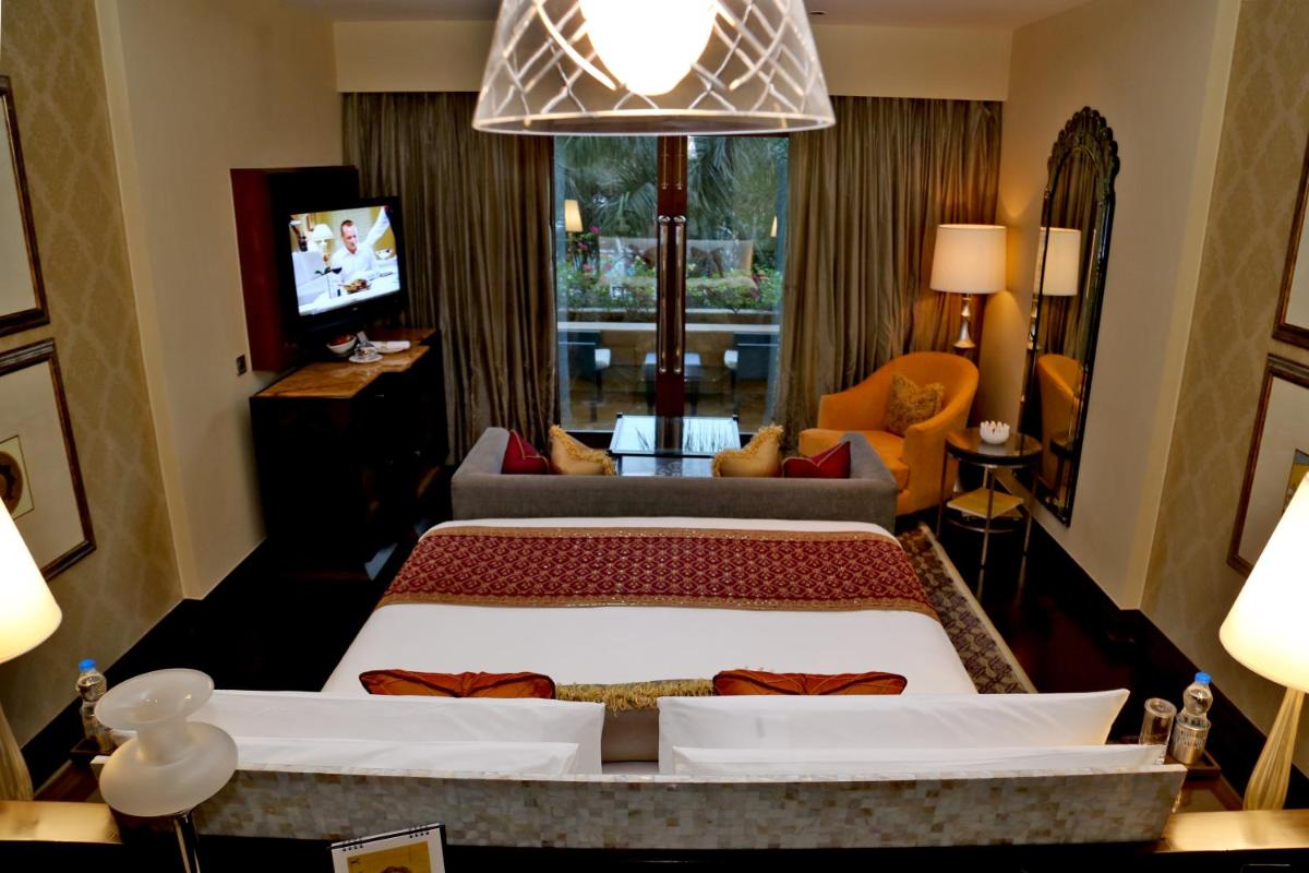 a bedroom with a large bed and a living room at The Leela Palace Udaipur in Udaipur