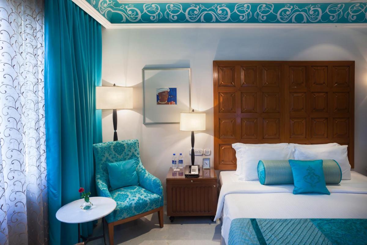 a hotel room with a bed and a chair at Jai Mahal Palace in Jaipur