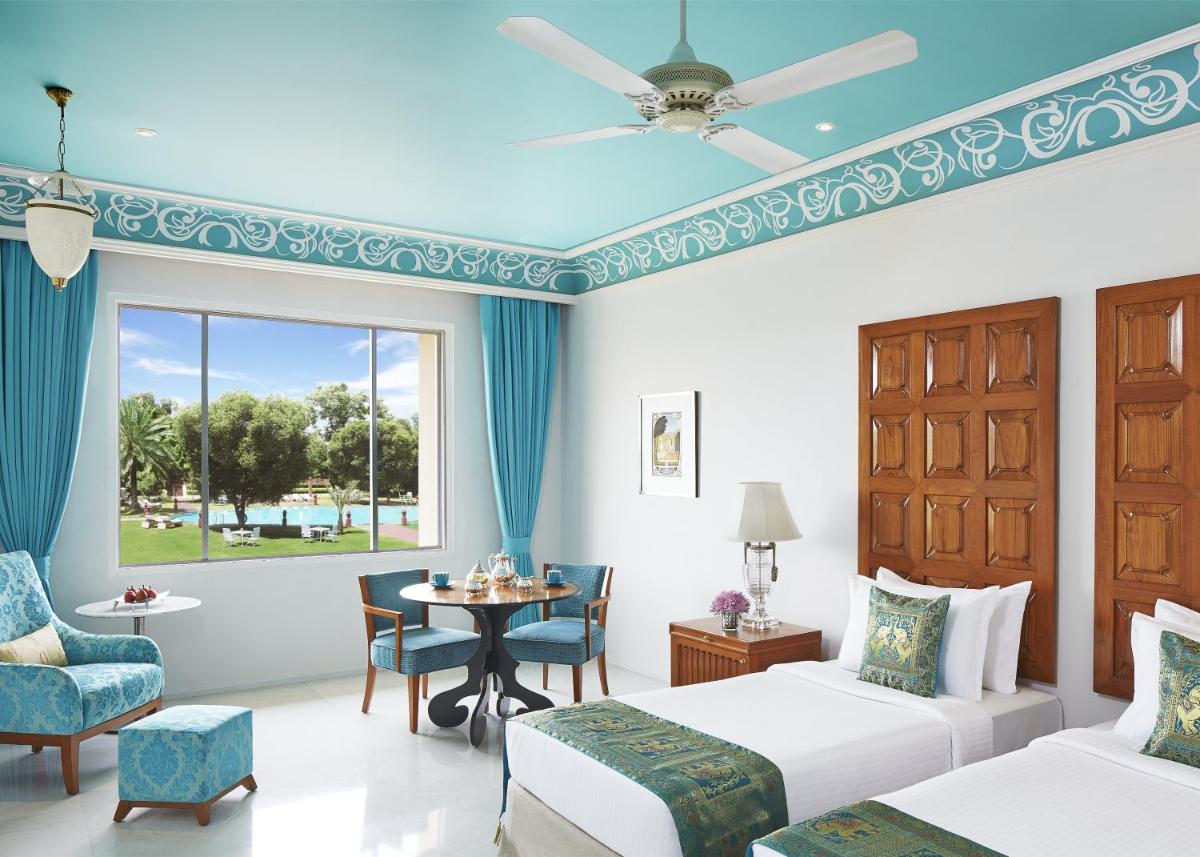 a hotel room with two beds and a table and chairs at Jai Mahal Palace in Jaipur