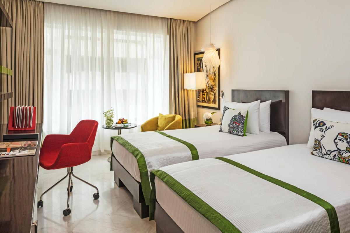 a hotel room with two beds and a red chair at The Park Chennai in Chennai a hotel room with two beds and a red chair at The Park Chennai in Chennai