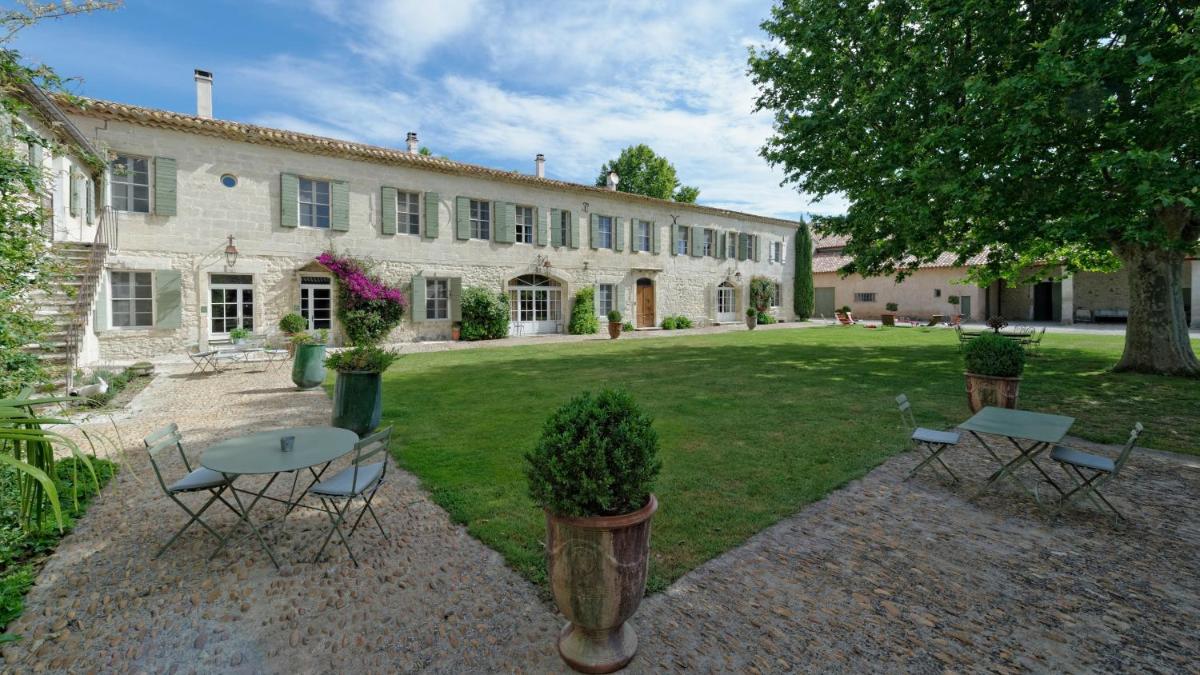 un bâtiment avec une table et des chaises dans une cour dans l'établissement HOTEL et APPARTEMENTS DOMAINE DES CLOS - Teritoria, à Beaucaire
