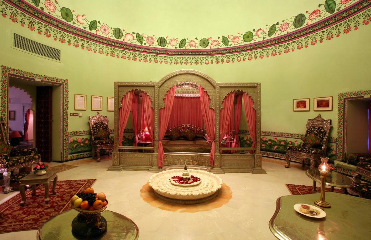 a living room with a bed and a table at Shiv Niwas Palace by HRH Group of Hotels in Udaipur