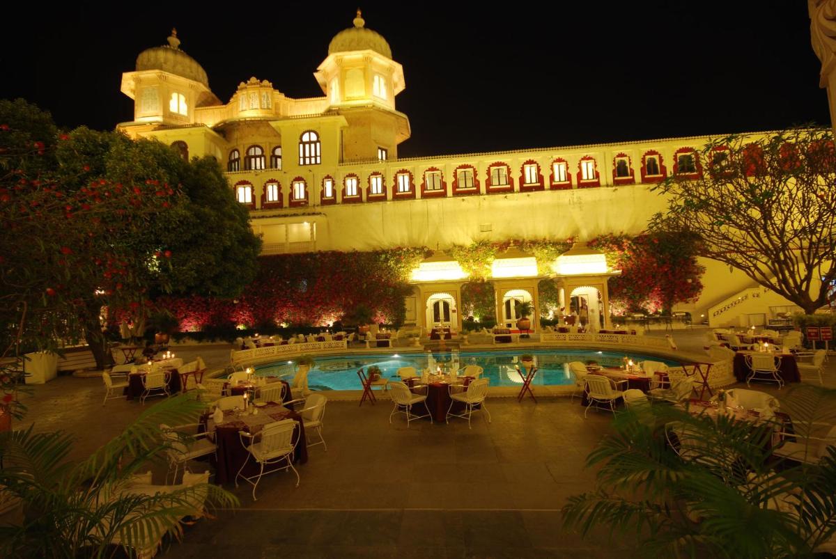 a large building with a swimming pool at night at Shiv Niwas Palace by HRH Group of Hotels in Udaipur