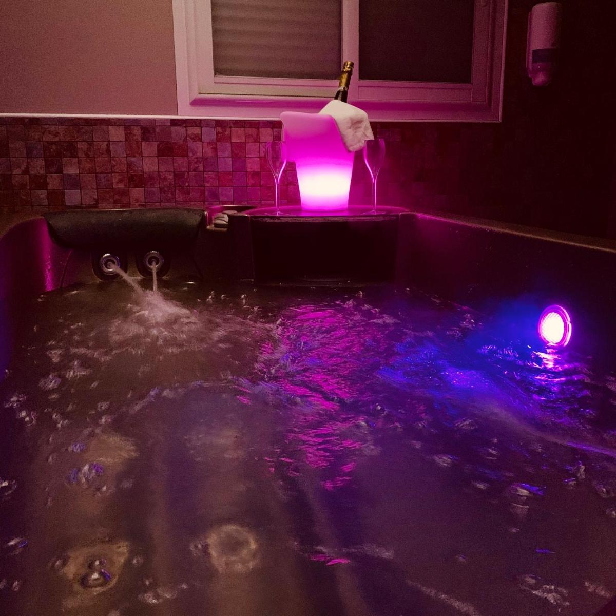 une baignoire avec des lumières violettes dans une salle de bain dans l'établissement Hôtel Le Belvedere, à Saint-Cyprien 39 autres photos