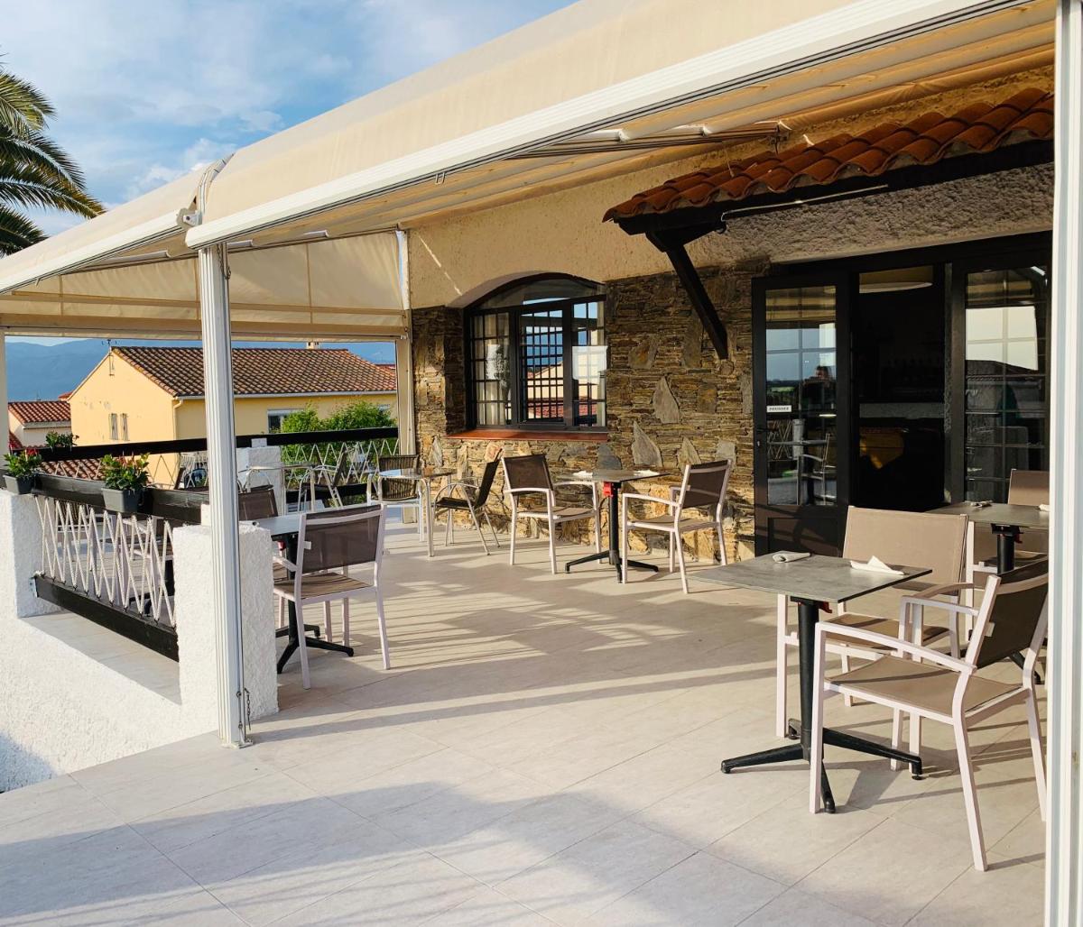 un patio avec des tables et des chaises sous un pavillon dans l'établissement Hôtel Le Belvedere, à Saint-Cyprien