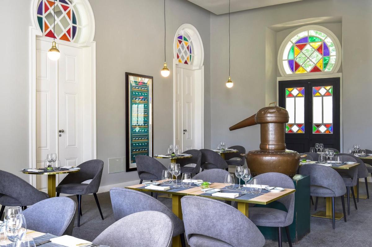 uma sala de jantar com mesas e cadeiras e vitrais em Central Monchique Hotel - Villa Termal Spa Resort - by Unlock Hotels em Monchique