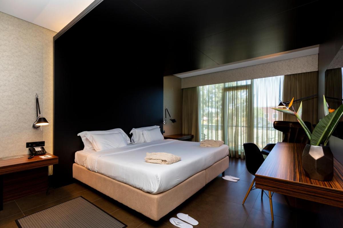 um quarto de hotel com uma cama e uma janela grande em Evidencia Belverde Hotel em Amora