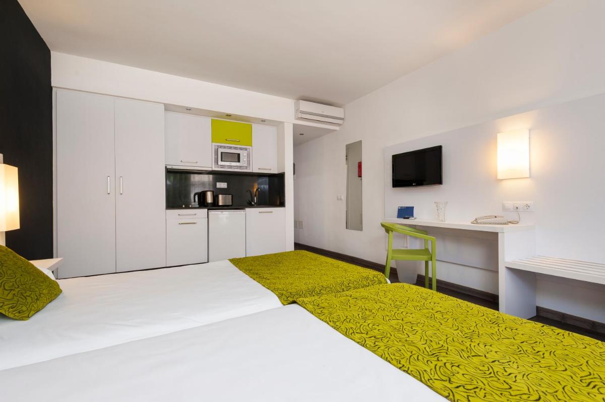 Una habitación blanca con una cama y una cocina. en Kn Aparthotel Columbus, en Playa de las Américas