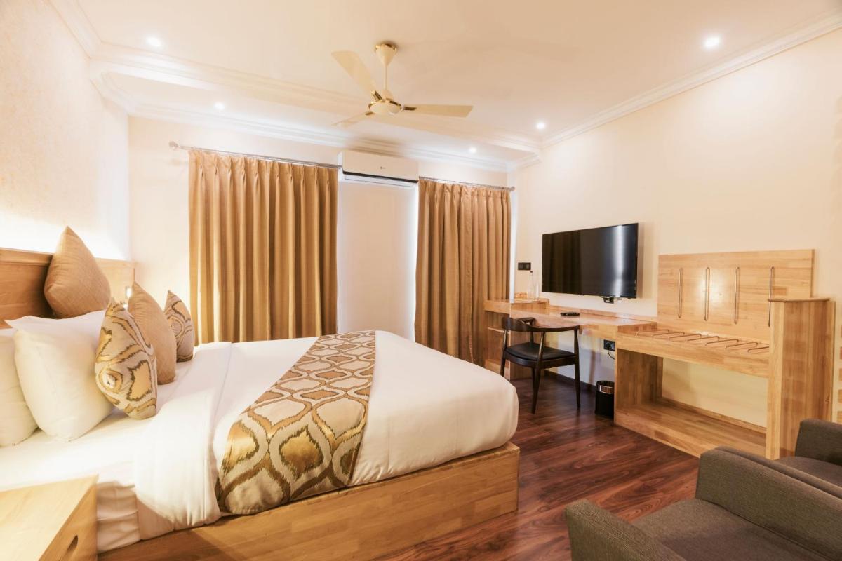 a bedroom with a bed and a desk with a television at The Panoramic Getaway in Munnar