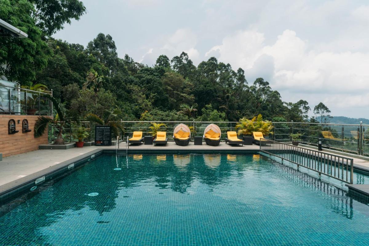 a swimming pool with lounge chairs and a mountain view at The Panoramic Getaway in Munnar