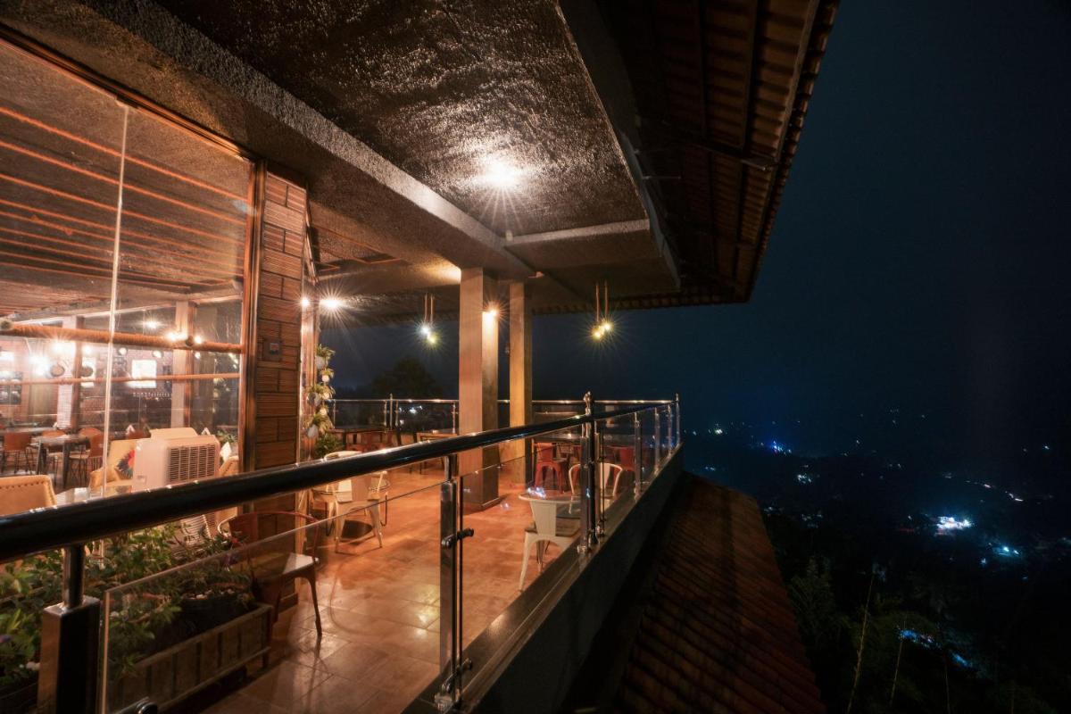 a balcony with a view of a city at night at The Panoramic Getaway in Munnar