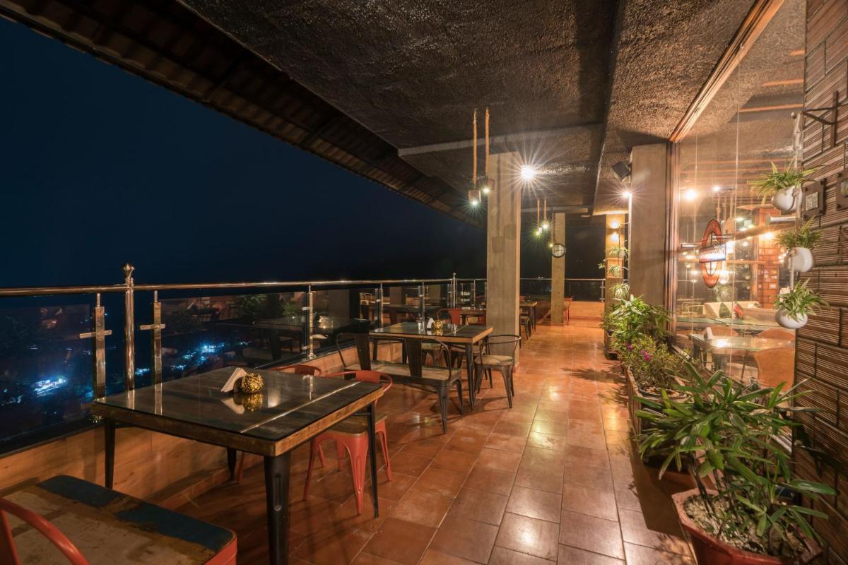 a restaurant with tables and chairs on a balcony at night at The Panoramic Getaway in Munnar