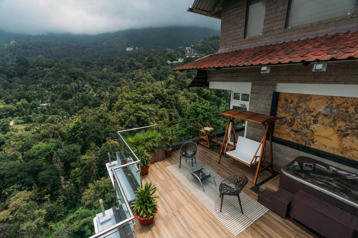 a balcony of a house with a view of the forest at The Panoramic Getaway in Munnar