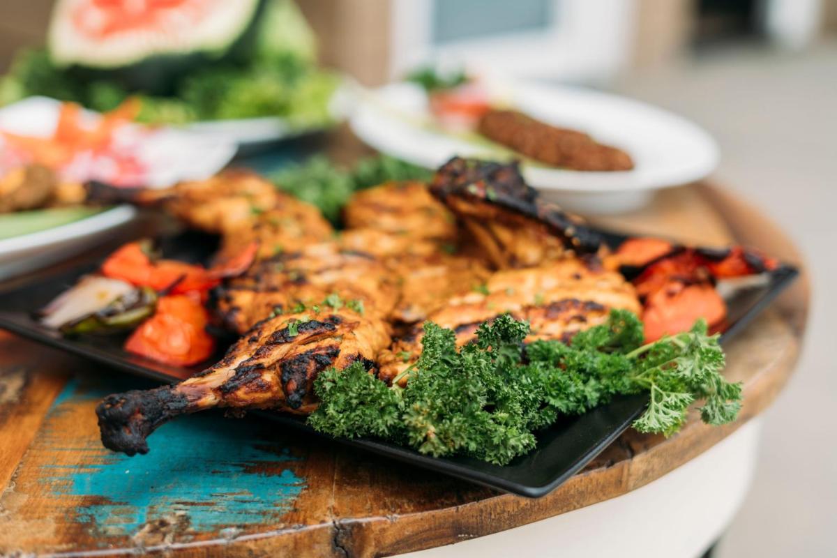 a plate of food with chicken and vegetables on a table at The Panoramic Getaway in Munnar