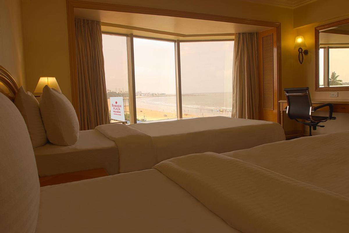 a hotel room with two beds and a view of the beach at Ramada Plaza By Wyndham Palm Grove in Mumbai