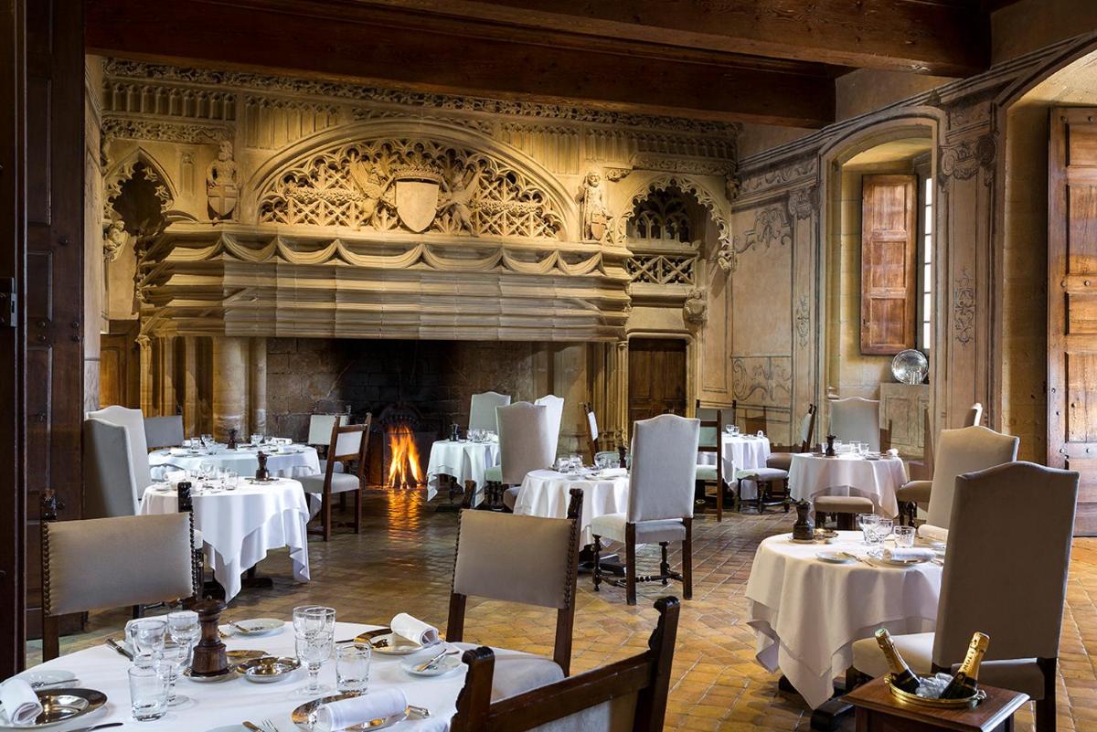 un restaurant avec des tables et des chaises blanches et une cheminée dans l'établissement Château de Bagnols, à Bagnols