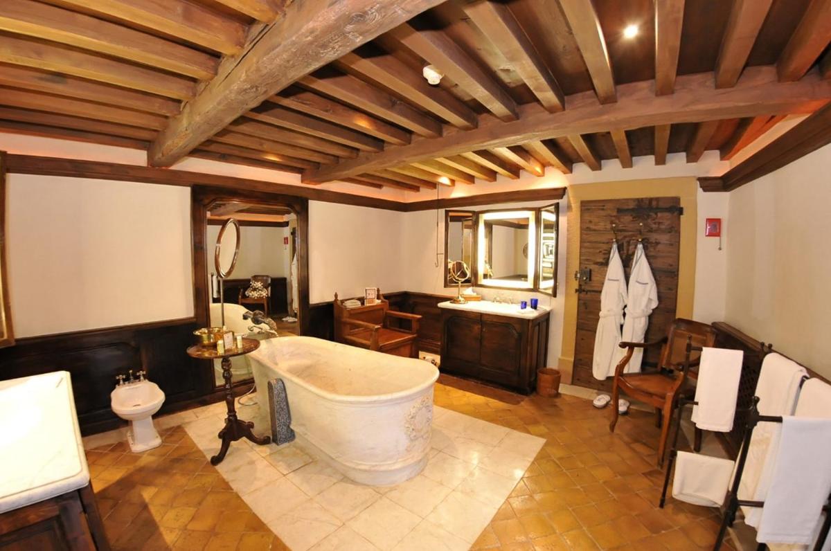 une grande salle de bain avec une baignoire et un lavabo dans l'établissement Château de Bagnols, à Bagnols