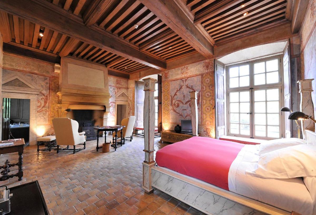 - une chambre avec un grand lit dans une pièce dotée d'une cheminée dans l'établissement Château de Bagnols, à Bagnols