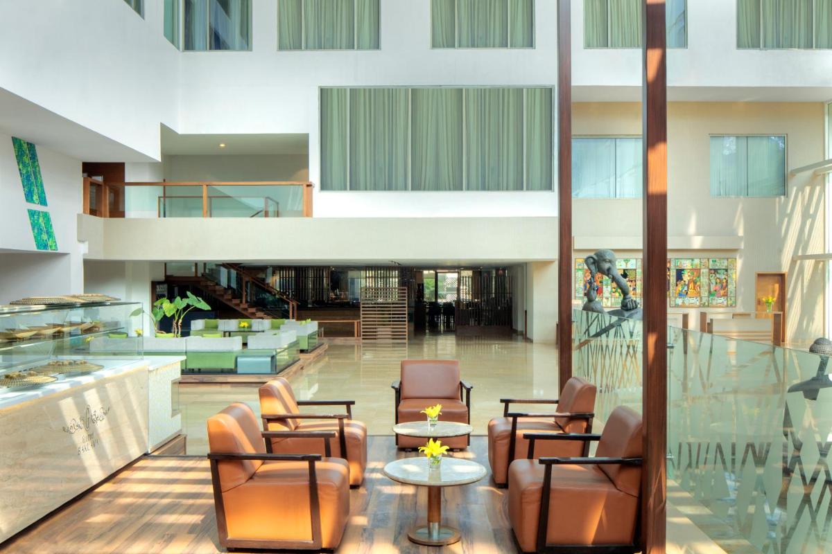 a lobby with chairs and tables in a building at Radisson Blu Plaza Hotel Hyderabad Banjara Hills in Hyderabad a lobby with chairs and tables in a building at Radisson Blu Plaza Hotel Hyderabad Banjara Hills in Hyderabad