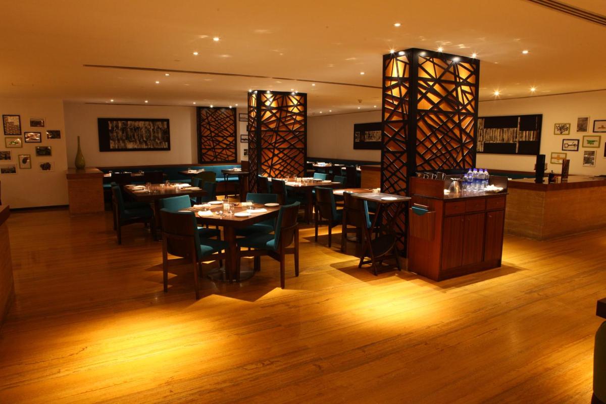 a restaurant with tables and chairs in a room at Radisson Blu Plaza Hotel Hyderabad Banjara Hills in Hyderabad a restaurant with tables and chairs in a room at Radisson Blu Plaza Hotel Hyderabad Banjara Hills in Hyderabad