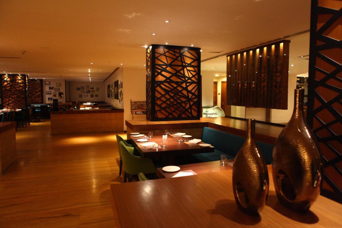 a dining room with a table and vases at Radisson Blu Plaza Hotel Hyderabad Banjara Hills in Hyderabad a dining room with a table and vases at Radisson Blu Plaza Hotel Hyderabad Banjara Hills in Hyderabad