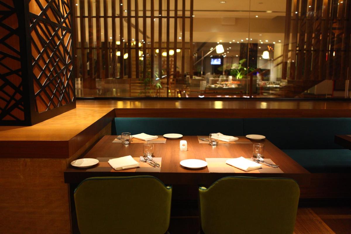 a wooden table in a restaurant with chairs and a table sidx sidx sidx at Radisson Blu Plaza Hotel Hyderabad Banjara Hills in Hyderabad a wooden table in a restaurant with chairs and a table sidx sidx sidx at Radisson Blu Plaza Hotel Hyderabad Banjara Hills in Hyderabad