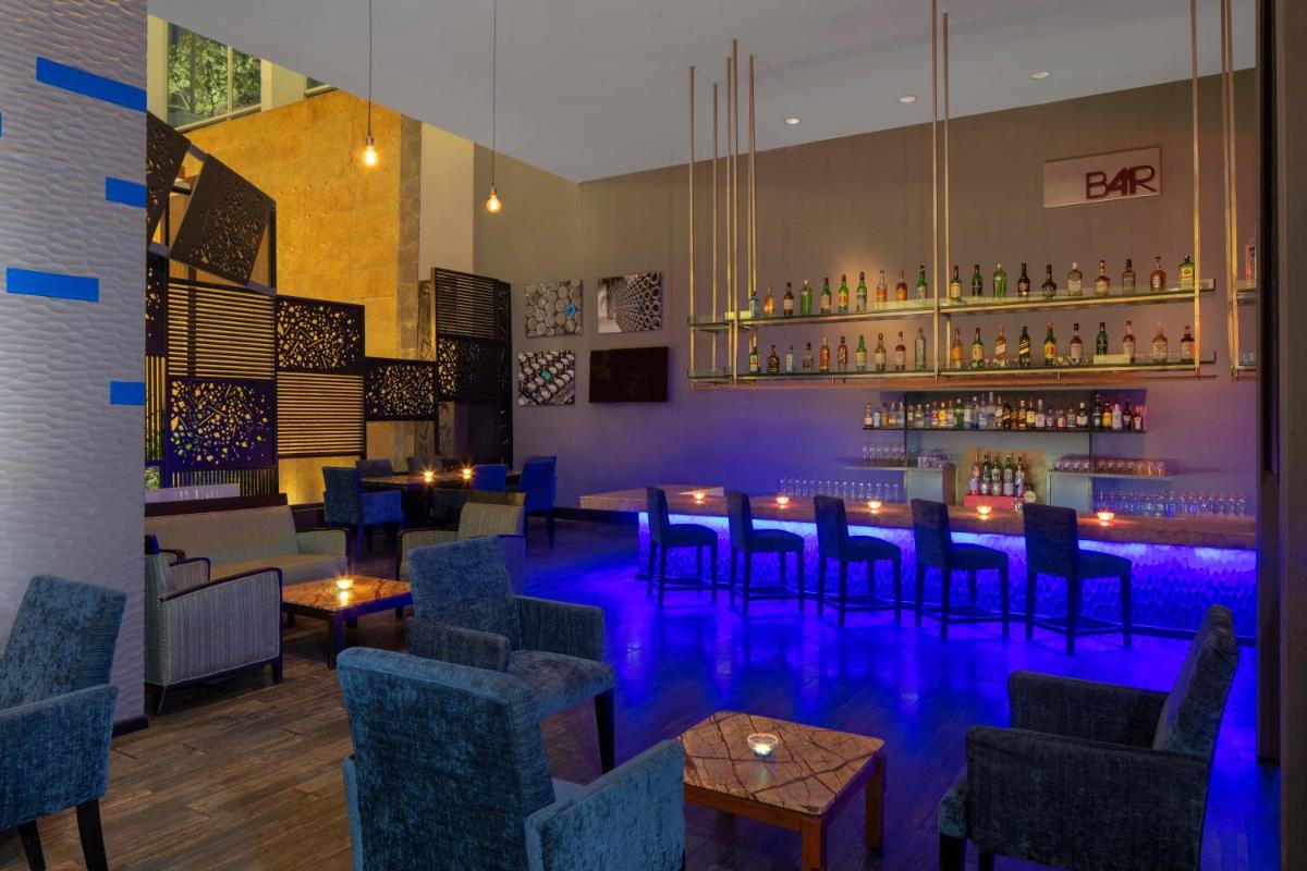 a bar with chairs and tables and a bar with blue lighting at Radisson Blu Plaza Hotel Hyderabad Banjara Hills in Hyderabad a bar with chairs and tables and a bar with blue lighting at Radisson Blu Plaza Hotel Hyderabad Banjara Hills in Hyderabad