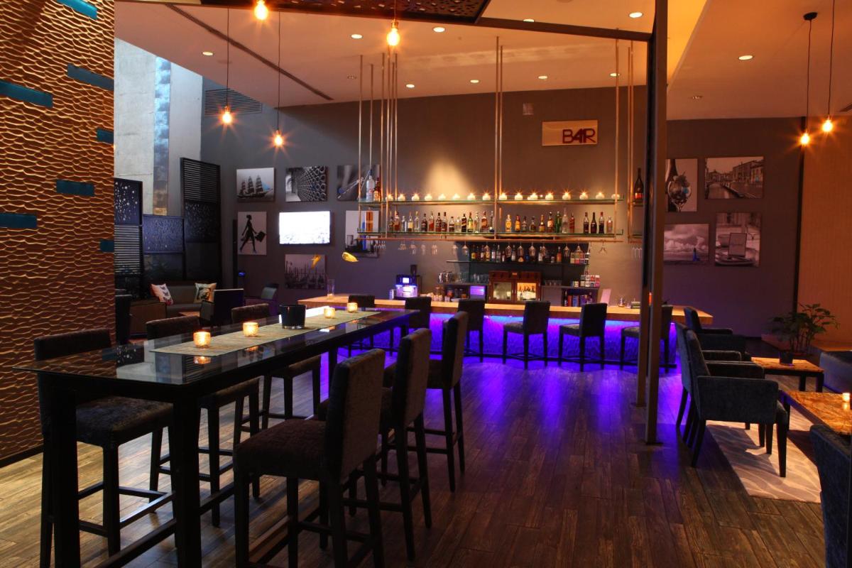 a restaurant with a long bar with purple lights at Radisson Blu Plaza Hotel Hyderabad Banjara Hills in Hyderabad a restaurant with a long bar with purple lights at Radisson Blu Plaza Hotel Hyderabad Banjara Hills in Hyderabad