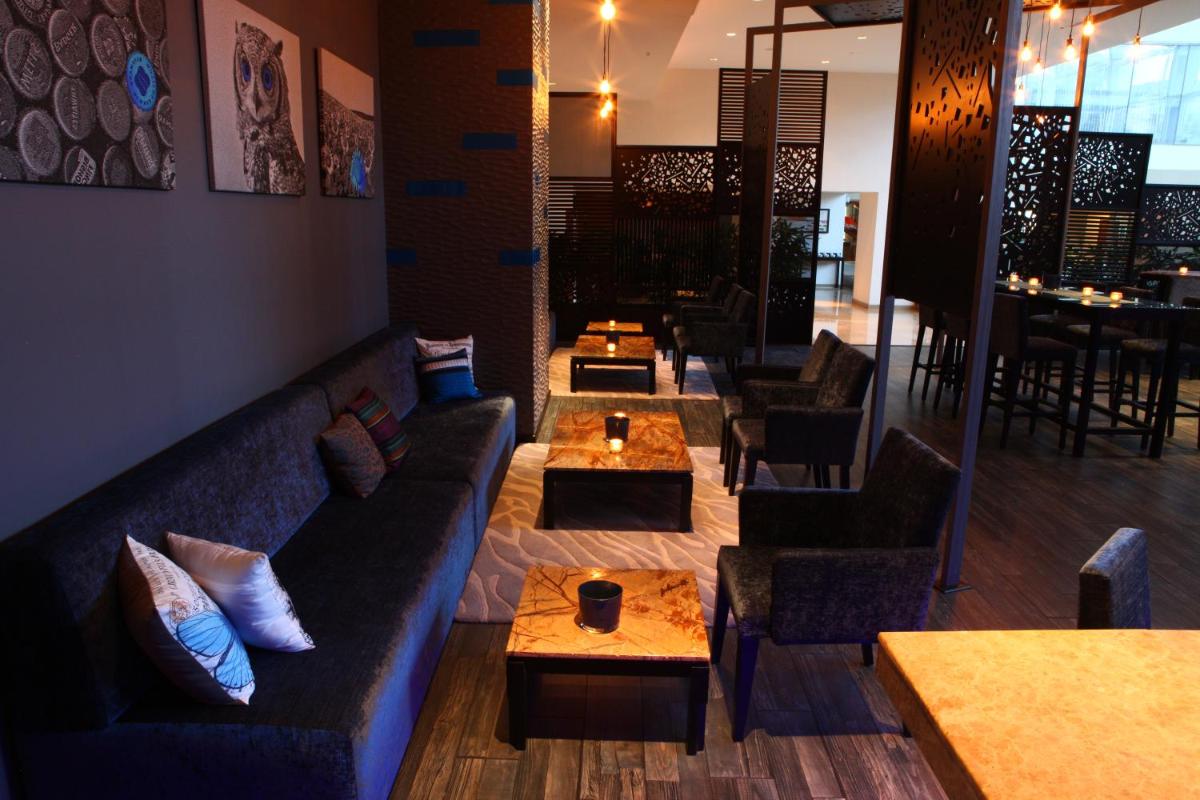 a living room with couches and tables in a restaurant at Radisson Blu Plaza Hotel Hyderabad Banjara Hills in Hyderabad a living room with couches and tables in a restaurant at Radisson Blu Plaza Hotel Hyderabad Banjara Hills in Hyderabad