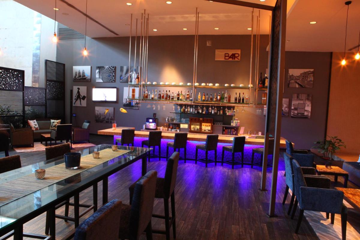 a bar with purple lighting in a restaurant at Radisson Blu Plaza Hotel Hyderabad Banjara Hills in Hyderabad a bar with purple lighting in a restaurant at Radisson Blu Plaza Hotel Hyderabad Banjara Hills in Hyderabad