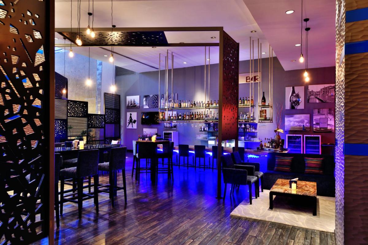 a bar with black tables and chairs and purple lighting at Radisson Blu Plaza Hotel Hyderabad Banjara Hills in Hyderabad a bar with black tables and chairs and purple lighting at Radisson Blu Plaza Hotel Hyderabad Banjara Hills in Hyderabad