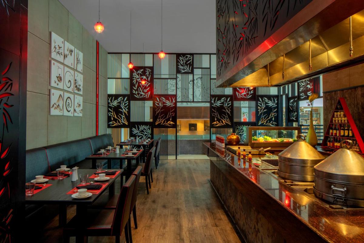 a restaurant with long tables and a buffet at Radisson Blu Plaza Hotel Hyderabad Banjara Hills in Hyderabad a restaurant with long tables and a buffet at Radisson Blu Plaza Hotel Hyderabad Banjara Hills in Hyderabad