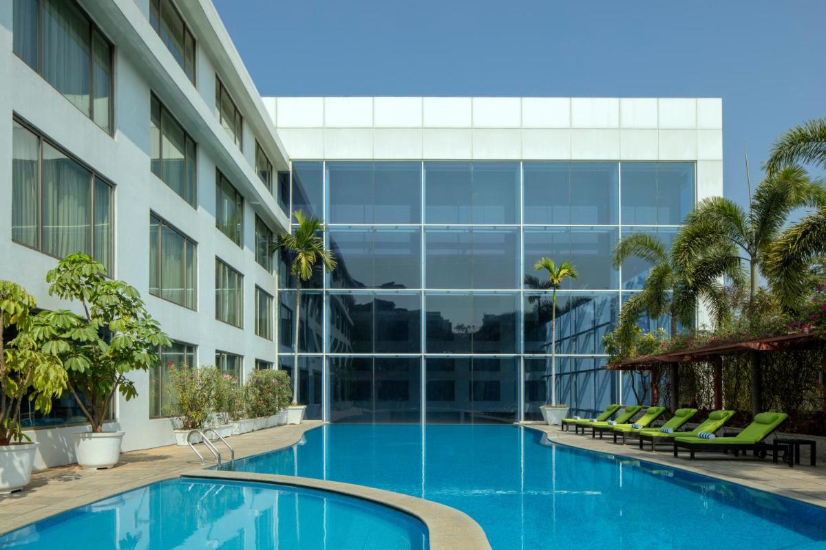 a swimming pool in front of a building at Radisson Blu Plaza Hotel Hyderabad Banjara Hills in Hyderabad a swimming pool in front of a building at Radisson Blu Plaza Hotel Hyderabad Banjara Hills in Hyderabad
