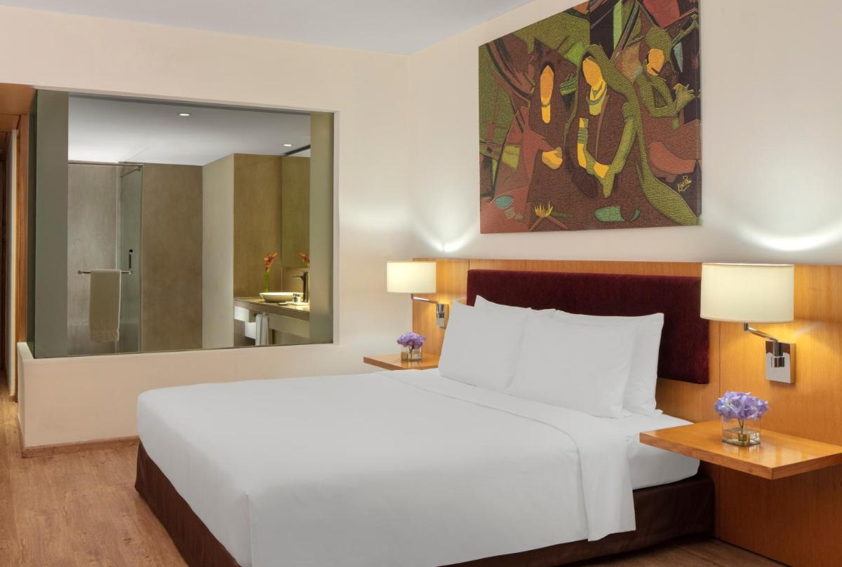 a bedroom with a white bed and a large mirror at Radisson Blu Plaza Hotel Hyderabad Banjara Hills in Hyderabad a bedroom with a white bed and a large mirror at Radisson Blu Plaza Hotel Hyderabad Banjara Hills in Hyderabad