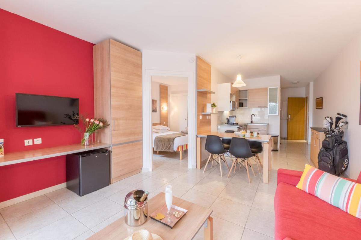 un salon avec un mur d'accent rouge dans l'établissement Résidence Hôtelière Natureva & Spa, au Cap d'Agde