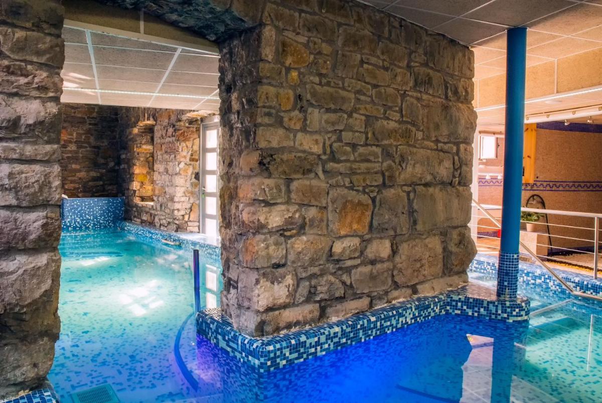 una piscina con una pared de piedra y agua azul en Balneario Caldas de Luna, en Caldas de Luna