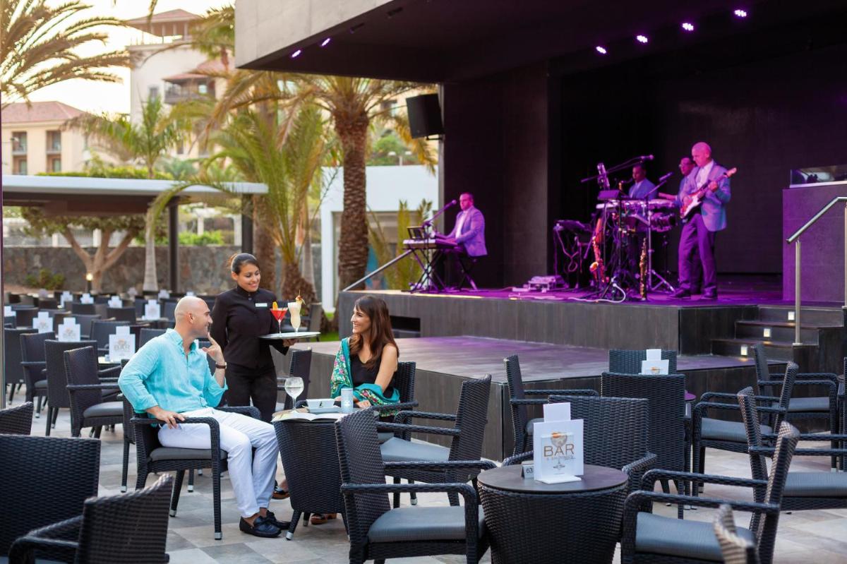 un grupo de personas sentadas en sillas delante de un escenario en Hotel Riu Palace Oasis, en Maspalomas