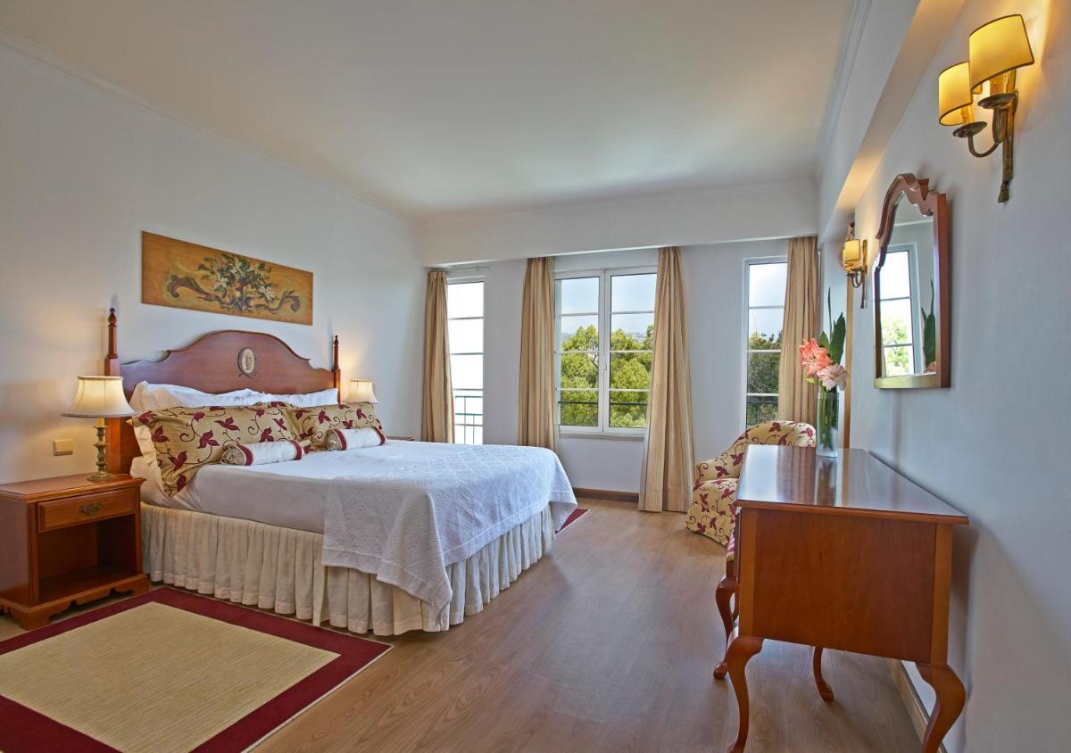 um quarto com uma cama, uma mesa e janelas em Quintinha Sao Joao Hotel & Spa no Funchal